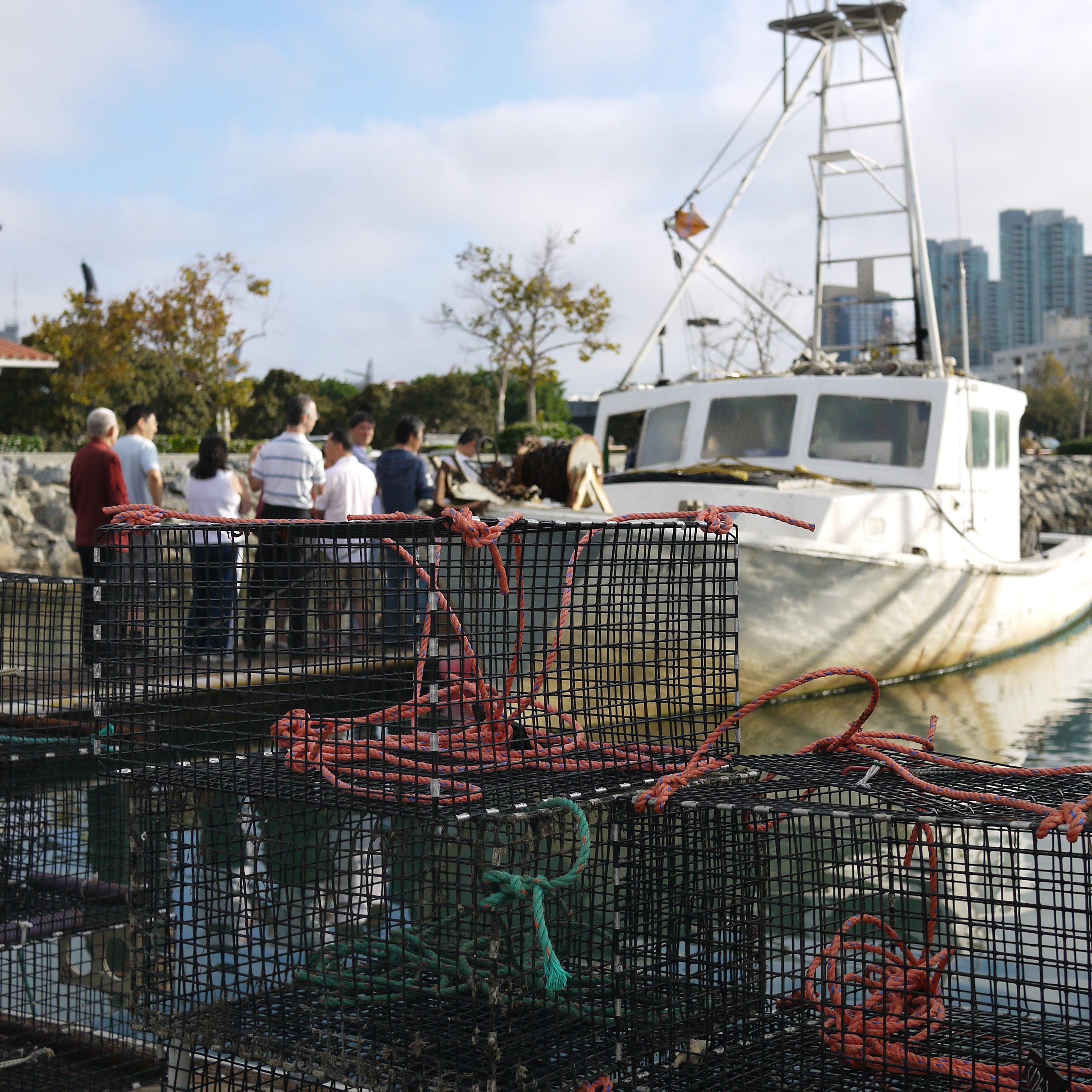 People on dock next to fishing boat with traps