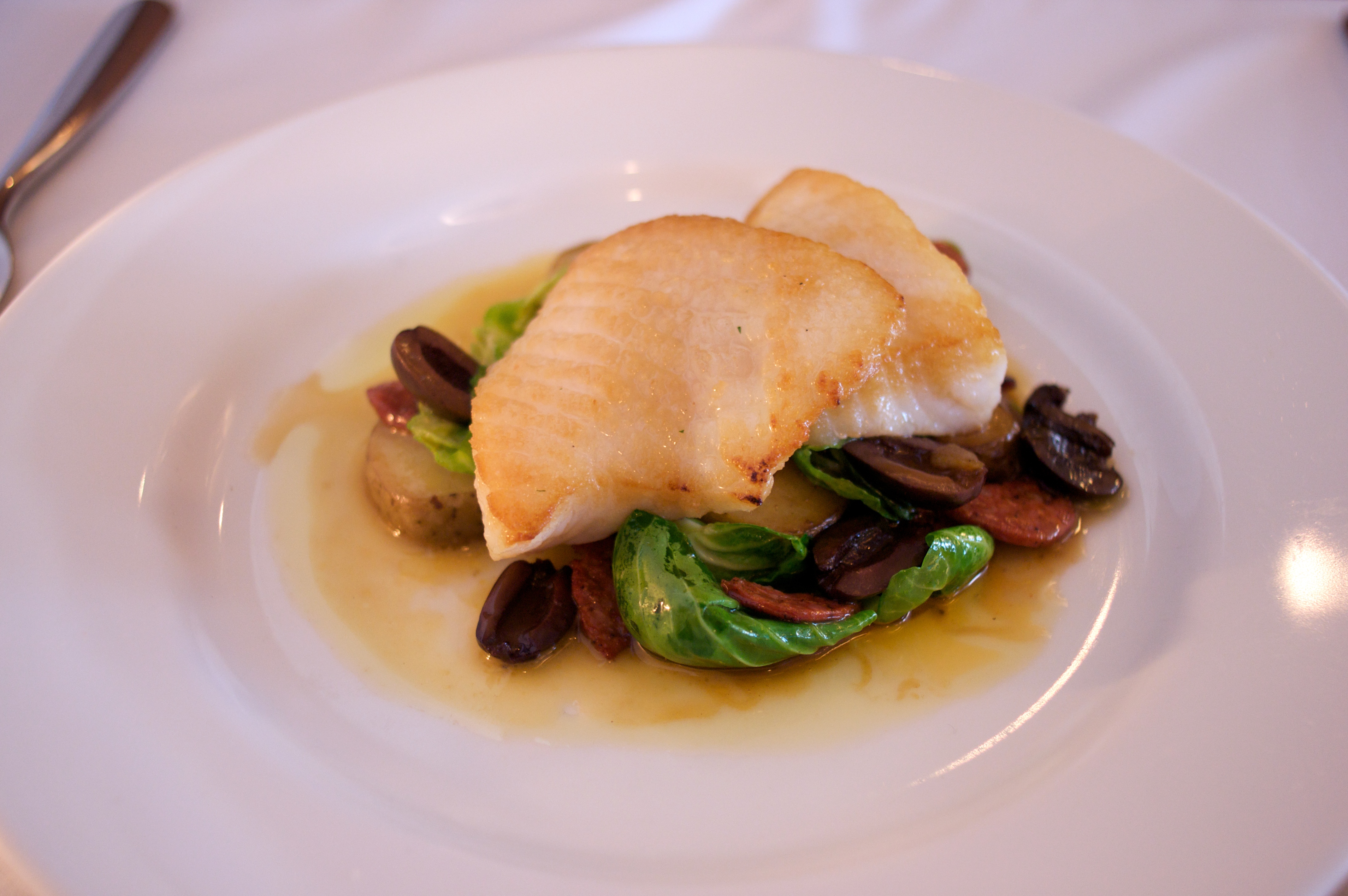 pan-seared lingcod with brussel sprout leaves, sausage, olives, and potato