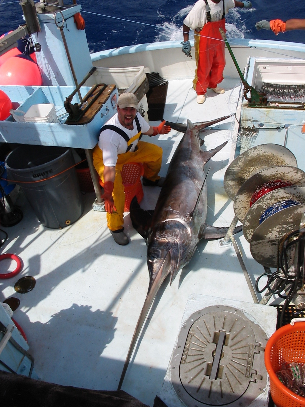 A fisherman poses with a swordfish on boat deck