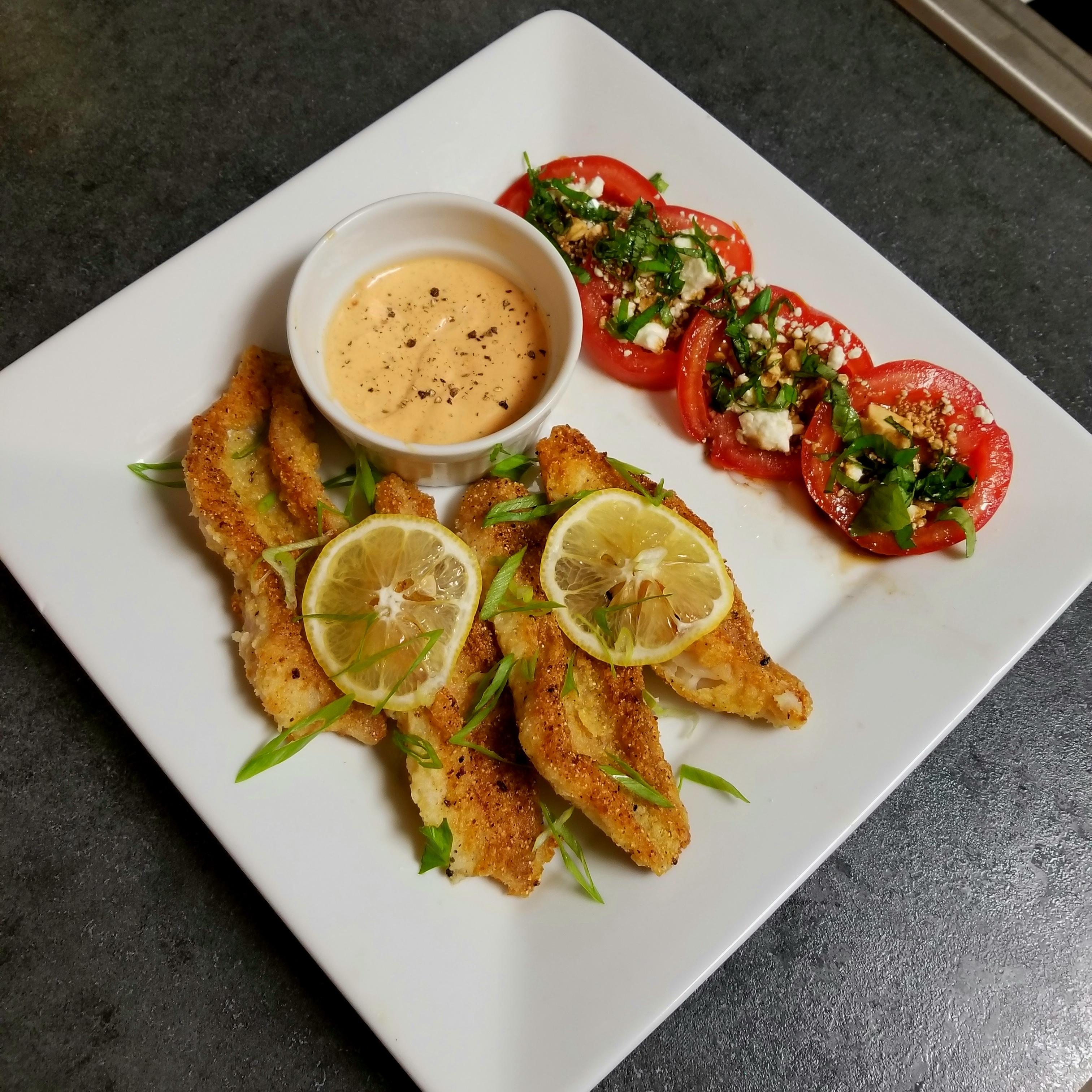 Pan fried ocean perch with lemon, spicy aioli sauce, and feta-basil tomatoes