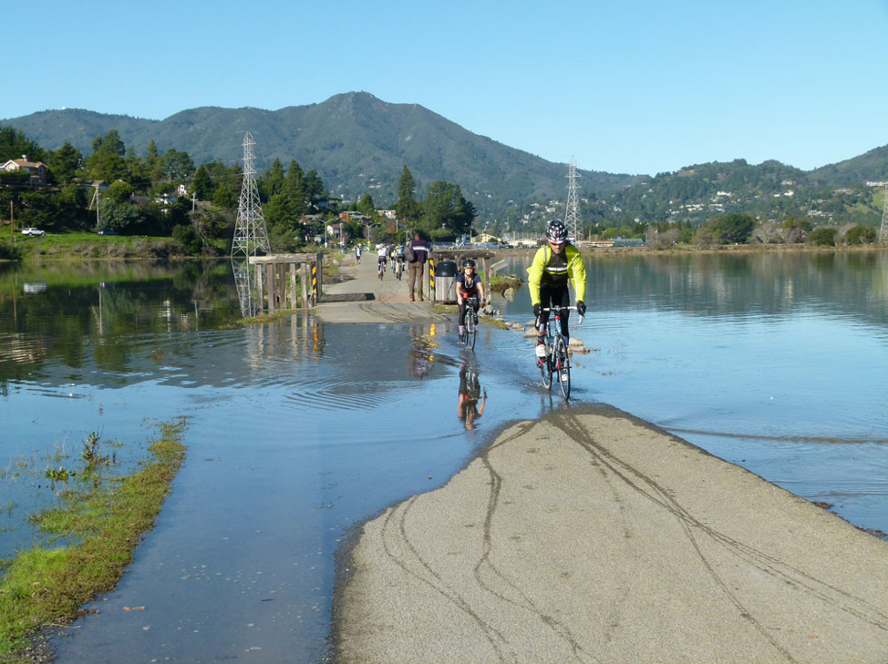 cyclists riding across a flooded path