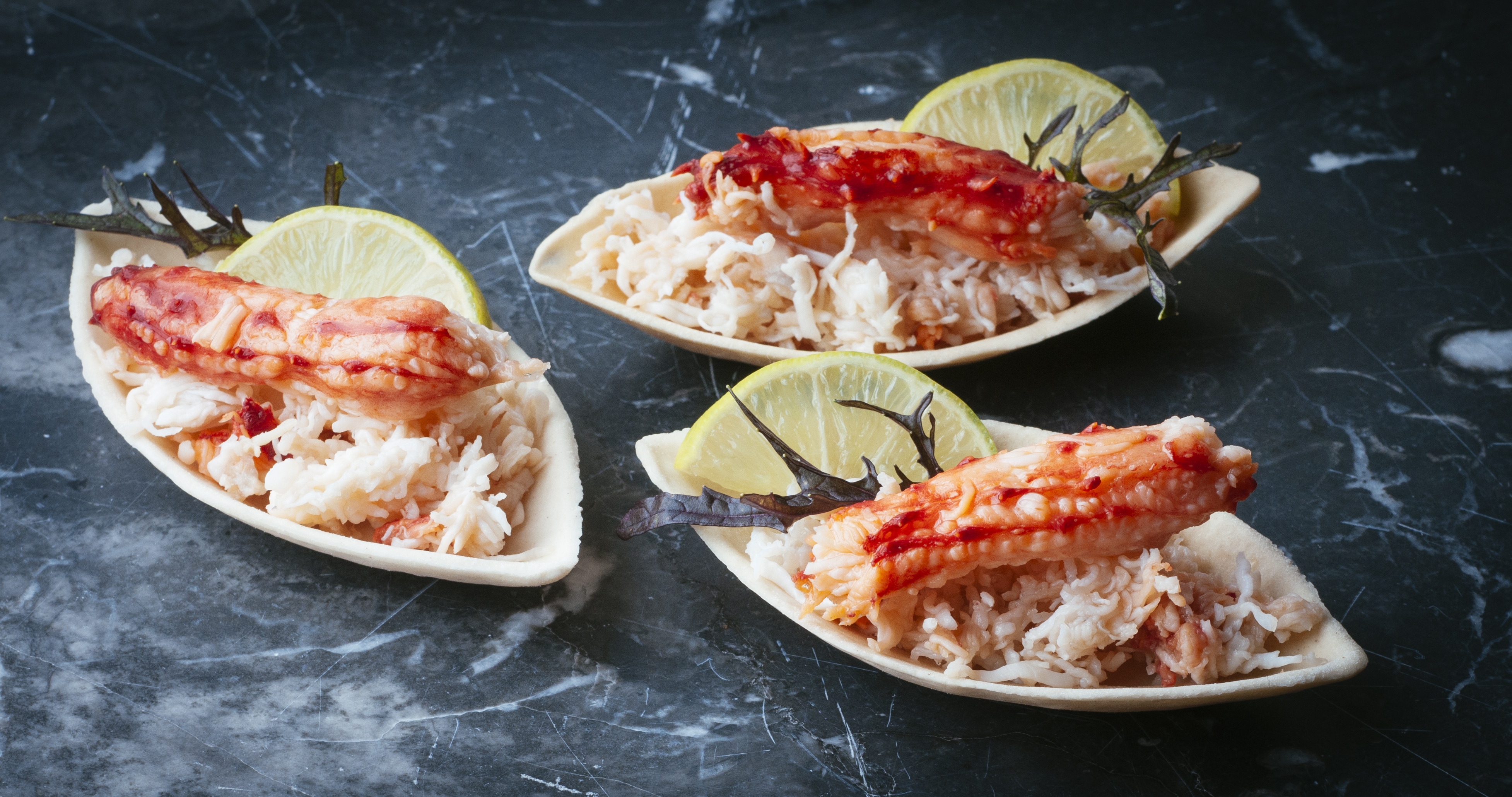 cooked crab laid on decorative platters, garnished with seaweed and lemon