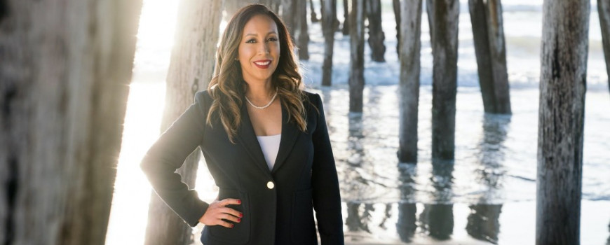 paloma aguirre, in a suit with pier and ocean in background