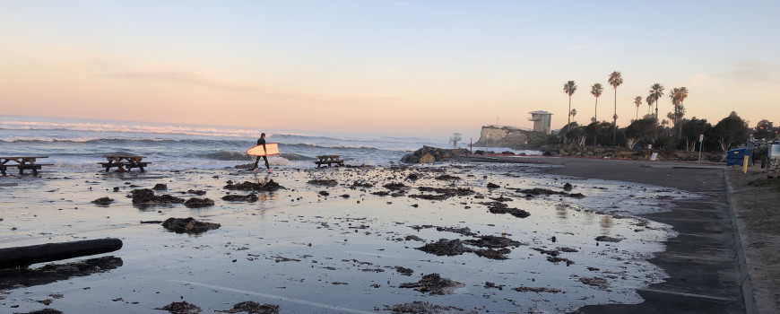 a surfer walks across a flooded parking lot