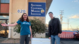 two researchers holding a cooler