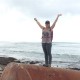 Michaela standing on a large metal drum on a beach