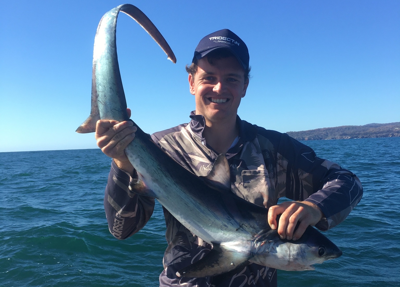 Fisherman holding up thresher shark.