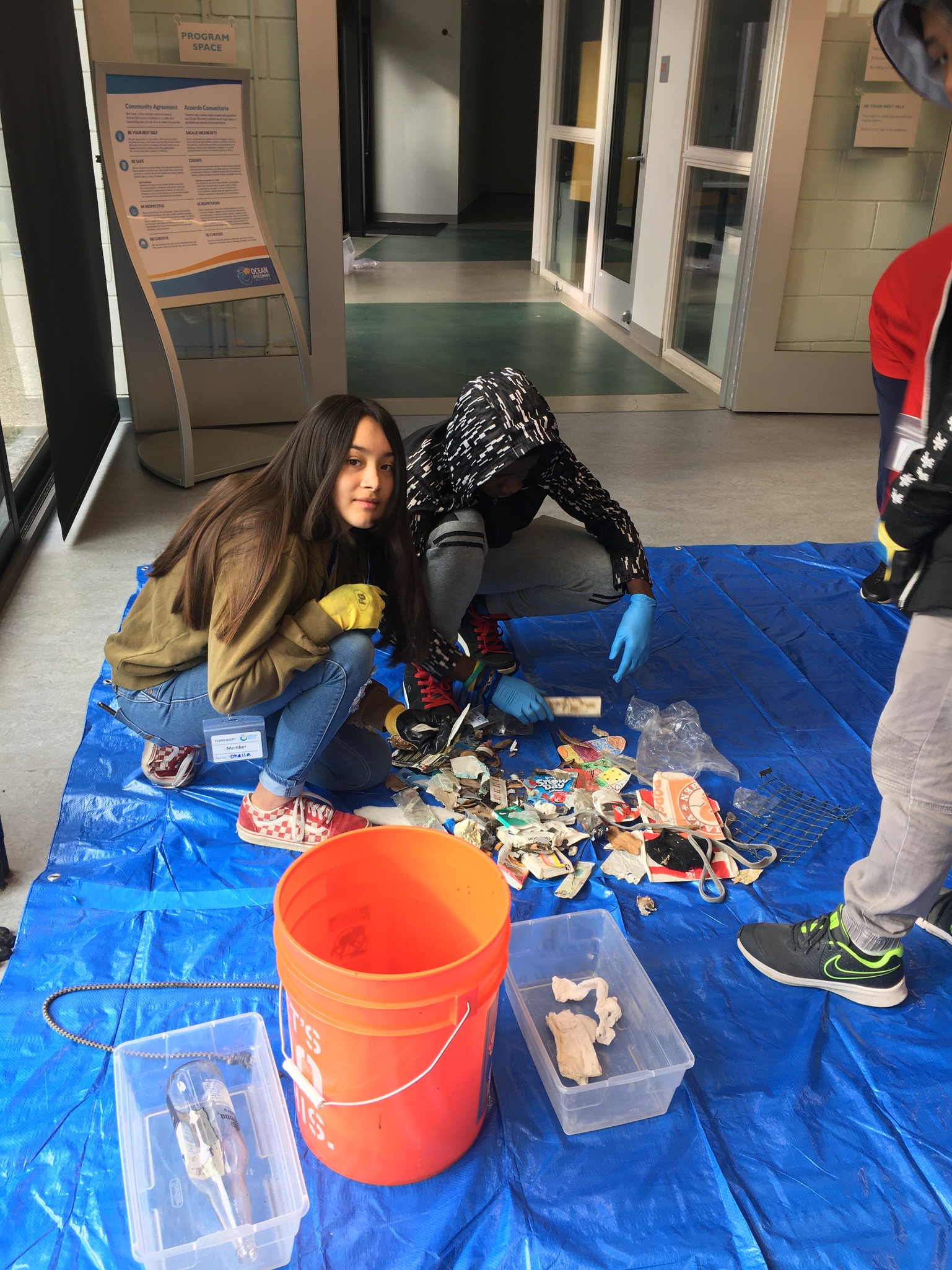 students sorting trash on a blue tarp