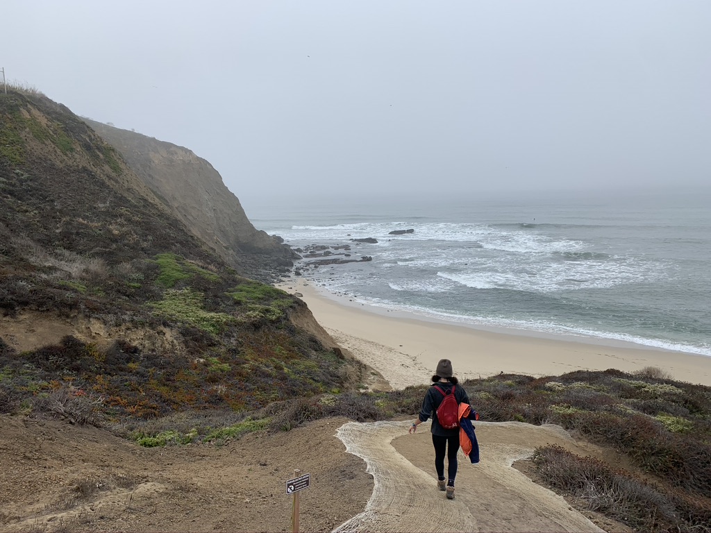 Woman walking down trail to the beach