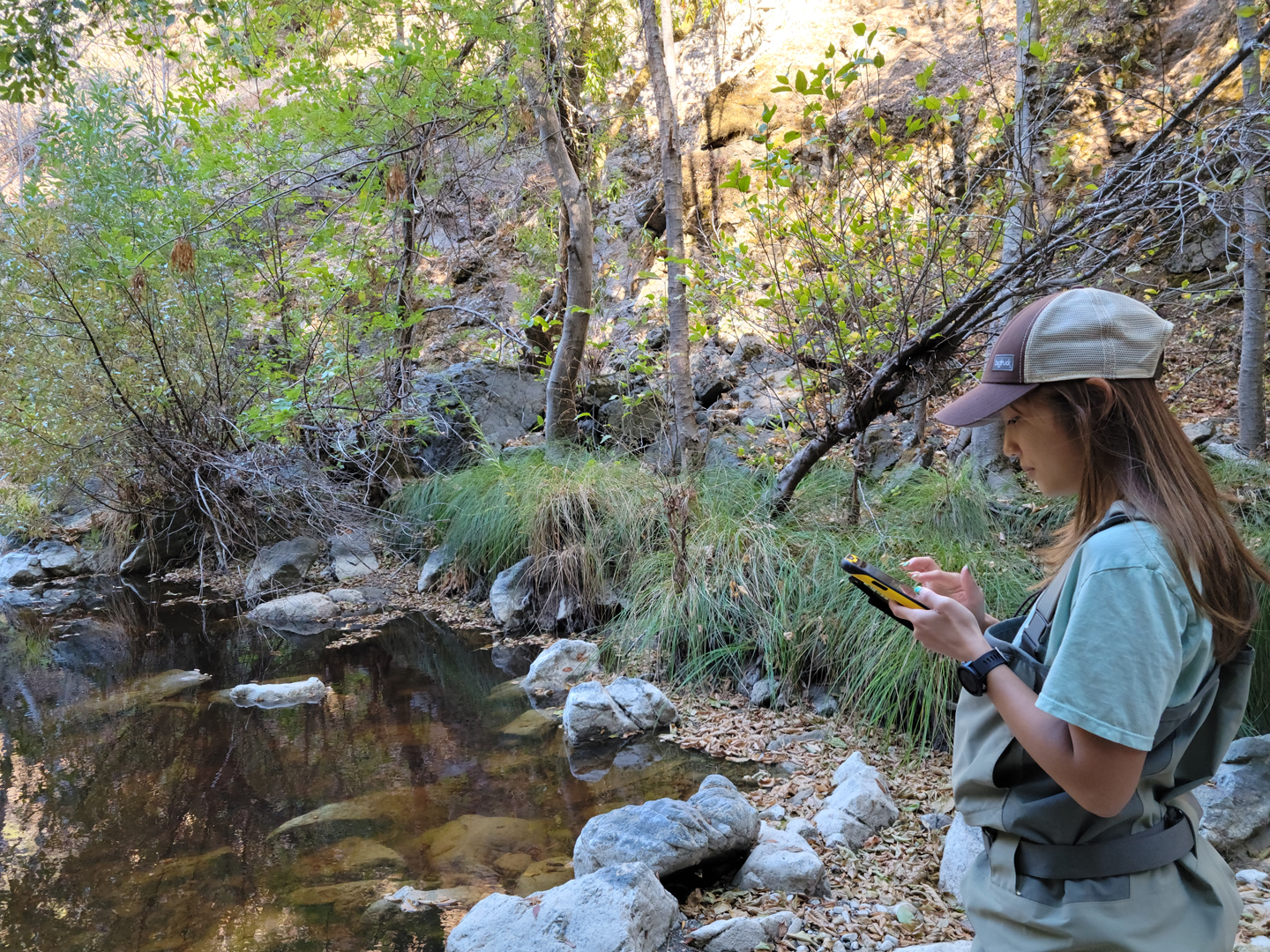 Internship Alumni, Suchanuch Kerdsinchai, collects wetted habitat data on a Trimble handheld device